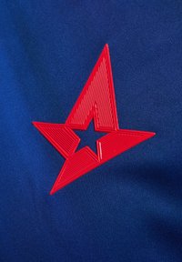 Rode rubberen sterlogo met gestructureerde lijnen op een effen blauwe stofachtergrond, met scherpe hoeken en een holle kern.