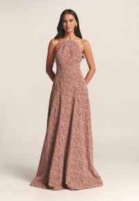 Rožinė gėlių rašto suknelė su apkabinamu kaklu, prigludusiu liemeniu ir laisvai krentančia sijonėle, puošta lapų raštu ir šoninėmis kišenėmis. Lygus, lengvas audinys.