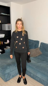 Pull noir avec accents en forme de cœur en cuivre, accompagné de leggings noirs et de chaussures à enfiler. La tenue présente une coupe décontractée et un tissu texturé.