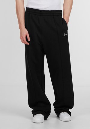 Sorte sweatpants med elastisk talje, sidelommer og et hvidt logo på hoften. Blød tekstur og afslappet pasform med lige ben design.