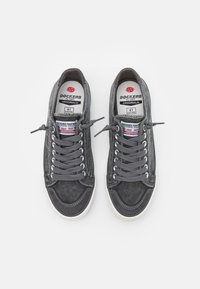 Gray canvas sneakers with rounded toe, contrasting white rubber sole, and gray laces. Features a logo and size label inside the shoe.