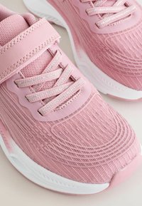 Paire de baskets roses pour enfants avec semelles blanches, tissu en mesh respirant, lacets et sangle velcro pour un maintien sécurisé.