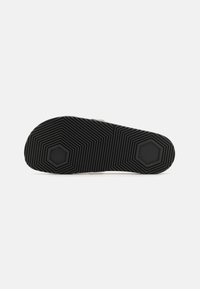 Talpa de pantof din cauciuc negru, cu un model texturat în zigzag și accente hexagonale. Prezintă un design plat și larg pentru stabilitate și aderență.