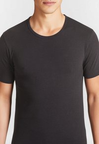 T-shirt nera a maniche corte realizzata in cotone leggero. Presenta un collo rotondo e una consistenza liscia con cuciture minime.