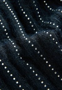 Černá texturovaná tkanina s vertikálními pruhy jasných rhinestone kamínků, vytvářejících dekorativní vzor. Měkký, načechraný povrch zdůrazňuje hloubku a detail.