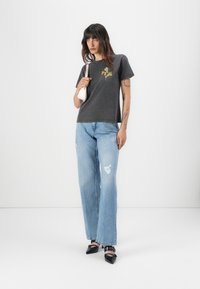T-shirt grigio a maniche corte con stampa floreale; abbinato a jeans a gamba larga, sbiaditi, di colore blu chiaro; scarpe nere a punta; borsa.