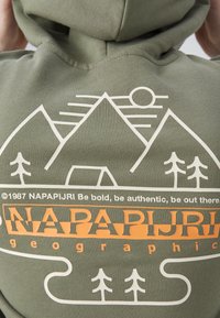 Dos de sweat à capuche avec graphisme montagne, soleil, arbres et tente, avec la marque "NAPAPIJRI" et le slogan "Soyez audacieux, soyez authentique, soyez dehors."