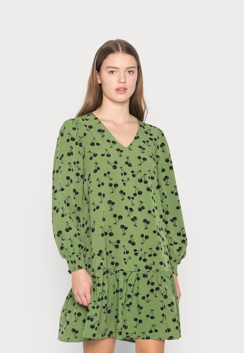 Vestido verde com decote em V, mangas longas abalonadas e bainha em camadas. Apresenta um padrão de cerejas pretas por todo o lado. Tecido de textura suave.