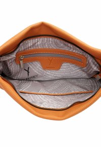 Interno di una borsa in pelle arancione con una fodera grigia a motivo. Presenta una tasca con zip e scomparti per un'organizzazione ottimale.