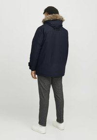 Diepblauwe pufferjas met een met bont gevoerde capuchon, met een relaxte pasvorm, elastische manchetten en een contrasterende stof op de rug.