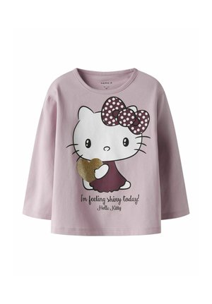 Lyserød langærmet t-shirt med en Hello Kitty grafik, der har en pokadotsløjfe og et glitrende hjerte, ledsaget af tekst.