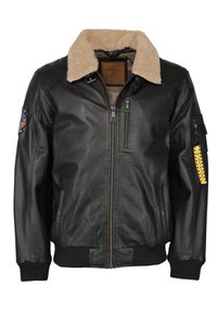 Schwarze Lederbomberjacke mit einem beigen Kunstfellkragen, Reißverschluss auf der Vorderseite, seitlichen Taschen und einem Aufnäher am linken Ärmel mit einem Emblem.