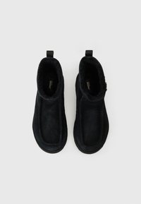 Black suede ankle boots with a soft, plush lining, smooth finish, and pull tabs at the back for easy wear. Flat rubber sole with stitching detail.