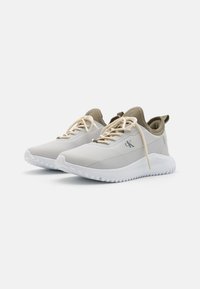 Scarpe da ginnastica bianche con una parte superiore liscia e leggermente texture, accenti beige, lacci crema e una suola bianca imbottita.