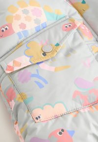 Colorful, padded jacket featuring playful animal patterns in pastel shades on a light gray background; includes a flap pocket with a button.