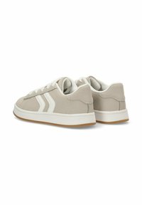 Zapatillas beige con cordones y rayas blancas, que cuentan con un material superior suave, un cuello acolchado y una suela de goma texturizada.