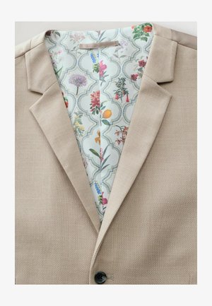 Blazer bej texturat cu rever căptușit și un buton negru, având o căptușeală colorată cu un model floral.