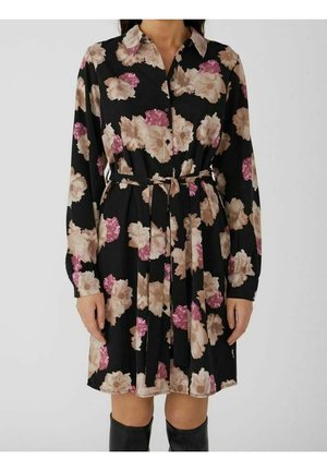 Schwarzes, langärmeliges Hemdkleid mit rosa und beigem Blumenmuster, Taillengürtel zum Binden, getragen mit schwarzen kniehohen Stiefeln.
