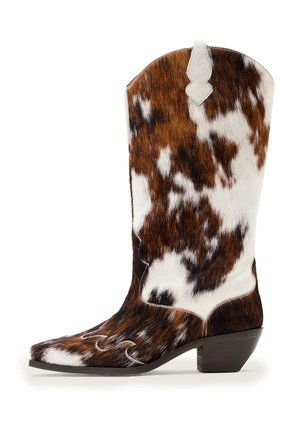 Botte western mi-mollet à motif peau de vache avec bout pointu, couture décorative, languette de traction et talon empilé bas en tons marron, blanc et noir.