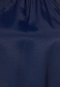 Mörkblått tyg med en slät, något glänsande yta. Samlad design längs den övre kanten som skapar mjuka veck. Inga synliga mönster eller detaljer.