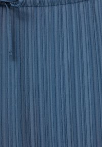 Blått texturerat tyg med vertikala veck och snörning i midjan. Materialet verkar lätt och luftigt.