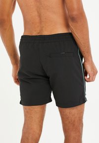 Bañador negro con cintura elástica, bolsillos laterales y un bolsillo trasero con solapa. Incluye una franja de acento color teal a los lados.