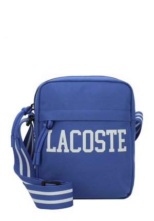 Bolso bandolera rectangular azul con texto blanco "LACOSTE" y correa azul ajustable con franjas horizontales blancas.