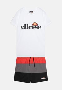 Vit t-shirt med en svart logotyp, tillsammans med shorts i röd, grå och svarta paneler. Har dragsko i midjan och sidfickor.