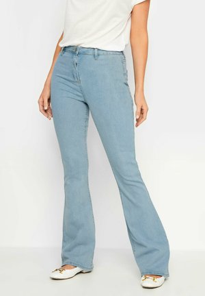Lichtblauwe uitlopende jeans van denim, met een hoge taille, vijf-pocket ontwerp en subtiele stiksels. Gecombineerd met witte instapflats.