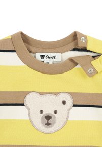 Geel en beige gestreept shirt met een zachte, textuurlijke berenkop applicatie op de voorkant. Inclusief een drukknoopsluiting op de schouder.