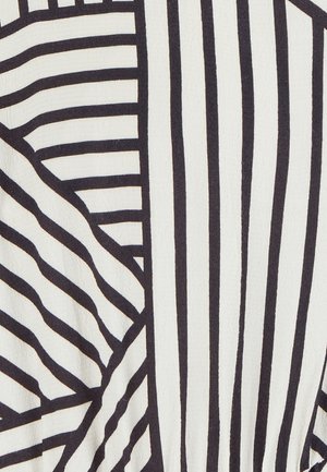 Tela a rayas en blanco y negro, con diferentes anchos de rayas y una superficie texturizada. El diseño incluye patrones diagonales y verticales.