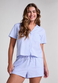 Set de pijama în carouri alb-albastre, format dintr-o bluză cu mânecă scurtă și butoni, împreună cu șorturi cu șnur, realizat dintr-un material moale, cu o croială lejeră.