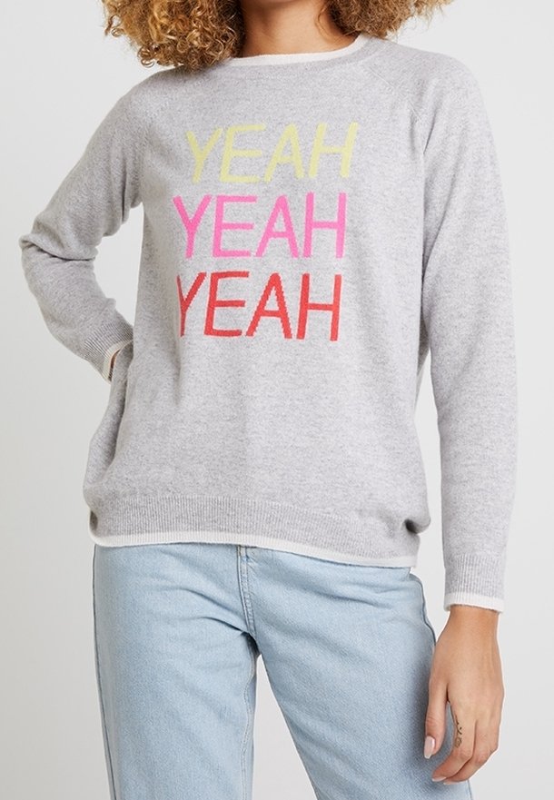 Grauer Pullover mit der Aufschrift "YEAH YEAH YEAH" in lebendigem Gelb, Pink und Rot. Weiches Material, lange Ärmel und gerippter Saum sowie Bündchen.
