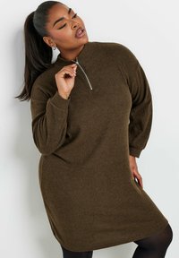 Abito pullover a coste marrone con colletto alto e dettaglio zip argentato. Presenta maniche lunghe e una vestibilità rilassata, che arriva a metà coscia.