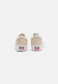 Bež nubuk tenisice s bijelim gumеним potplatom, s podstavljenim ovratnikom i Vans Off the Wall logom na peti. Minimalistički dizajn s čistim linijama.