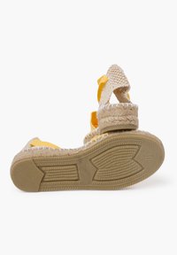 Sandalo espadrille con cinturini in canvas giallo, tomaia in beige intrecciata e tacco a cuneo rivestito in juta. Suola in gomma testurizzata con grip a motivi.