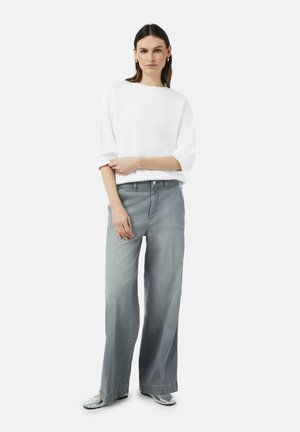 White, short-sleeve top paired with light gray, wide-leg jeans. The jeans feature a classic five-pocket design and subtle stitching accents.