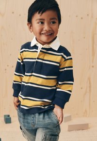 Polo rayé bleu marine et jaune à manches longues avec col blanc, associé à un jean en denim bleu clair. Conçu pour les enfants.