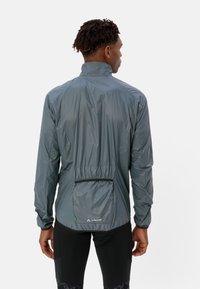 Leichte graue Jacke mit hohem Kragen, elastischen Bündchen und einer hinteren Reißverschlusstasche. Glatte Textur mit minimalistischen Designdetails.