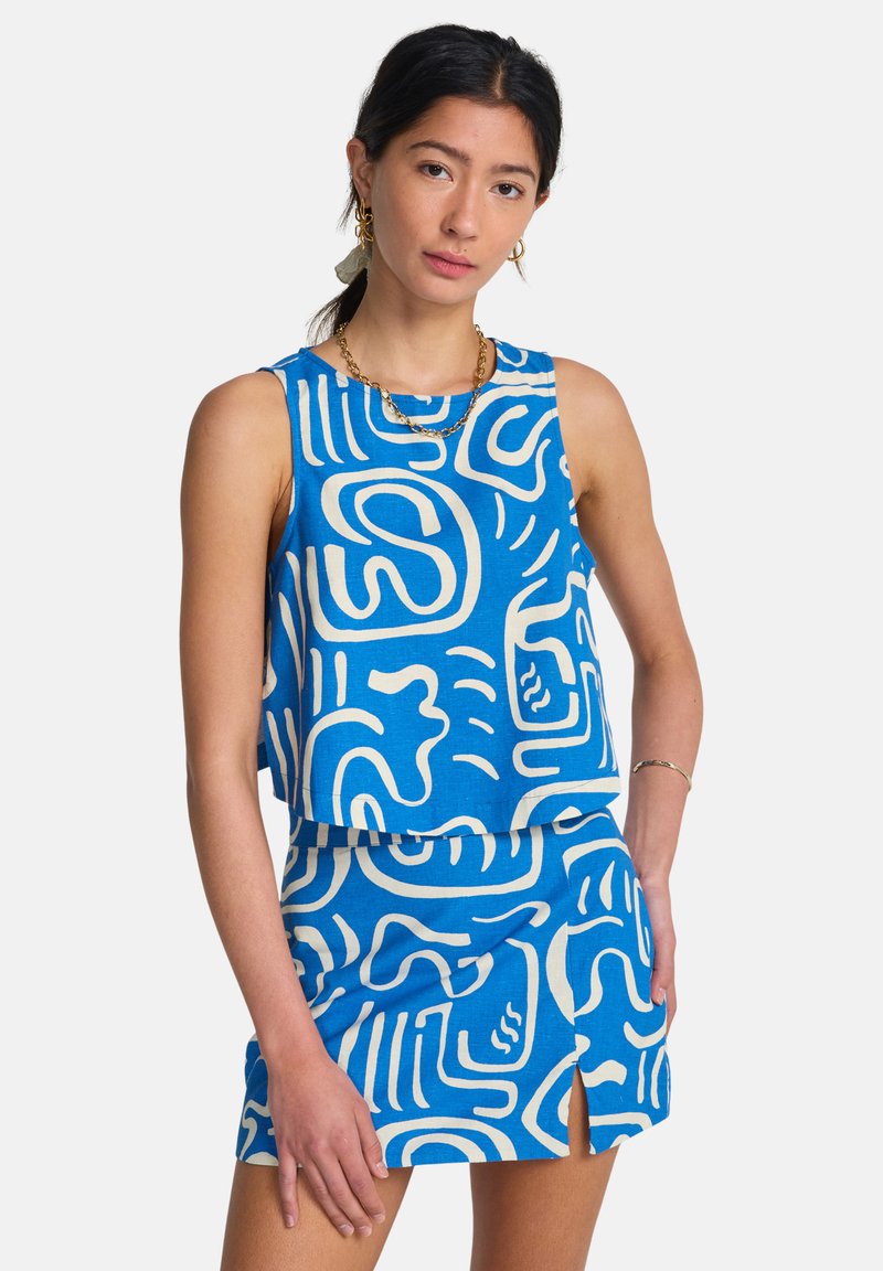 Σετ μπλε crop top και φούστα με σχέδια, με αφηρημένα λευκά μοτίβα. Το ύφασμα φαίνεται υφασμένο, με άνετη εφαρμογή και άνοιγμα στο πλάι της φούστας.