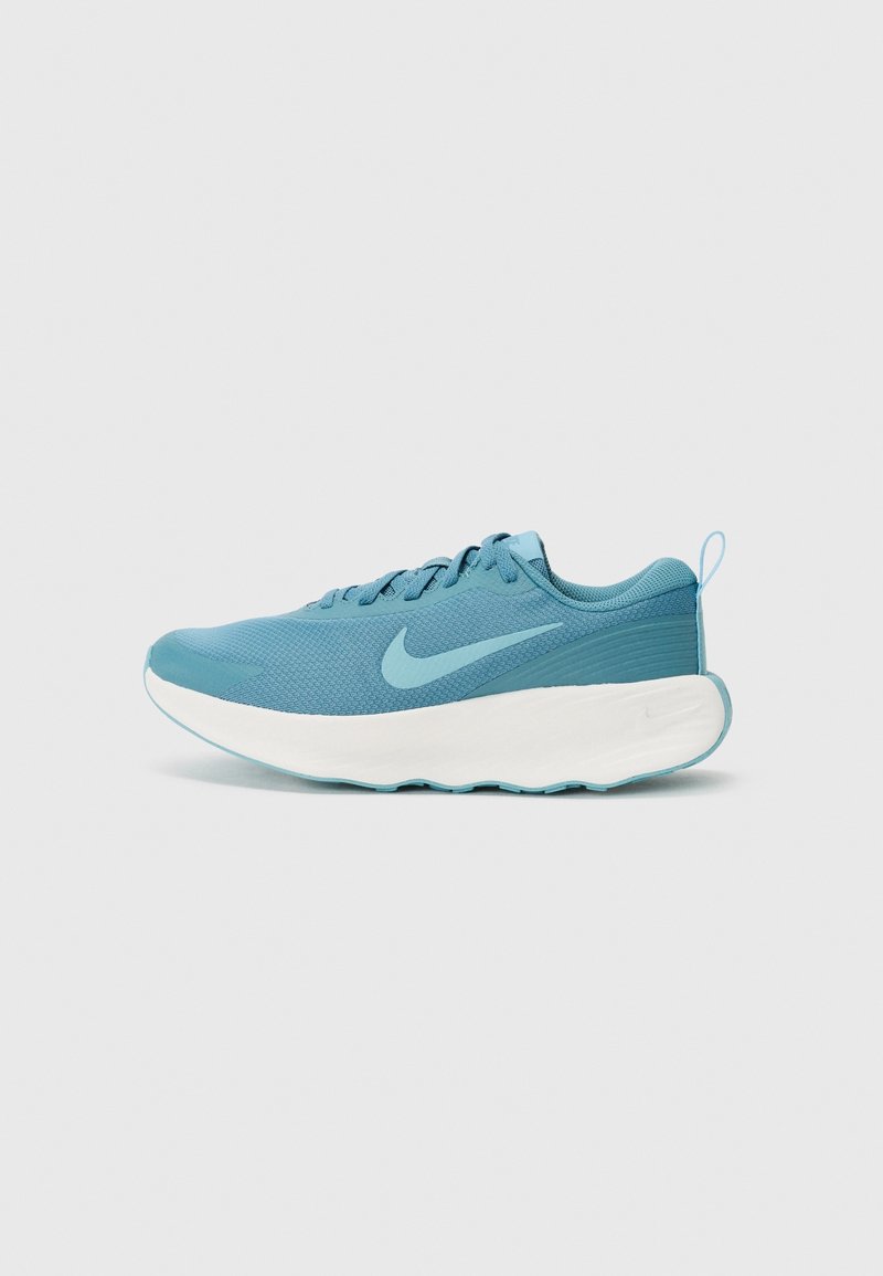 Baskets de sport bleu clair avec une tige en mesh, un col rembourré et une semelle blanche. Présente un logo swoosh bien en vue sur le côté et un accent texturé au niveau du talon.