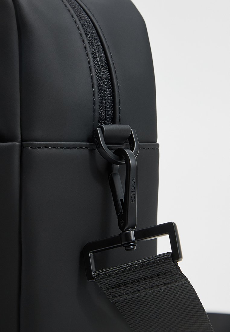 Schwarzer Rucksack mit mattem Finish, ausgestattet mit einem auffälligen Reißverschluss, strukturiertem Gurt und verstellbarem Clipsystem. Glattes, strapazierfähiges Material.