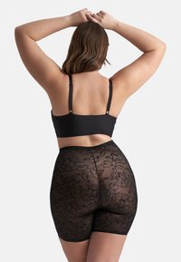 Svart spets bodysuit med blommönster, med justerbara axelband och en figurnära design som framhäver silhuetten.