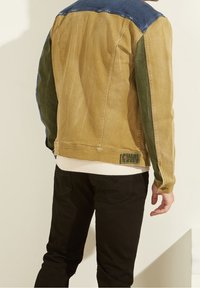 Bruine en groene kleurgeblokte denimjack met een blauwe yoke, slim fit en contrasterende stiksels. Heeft een achterpatch en geribde manchetten.