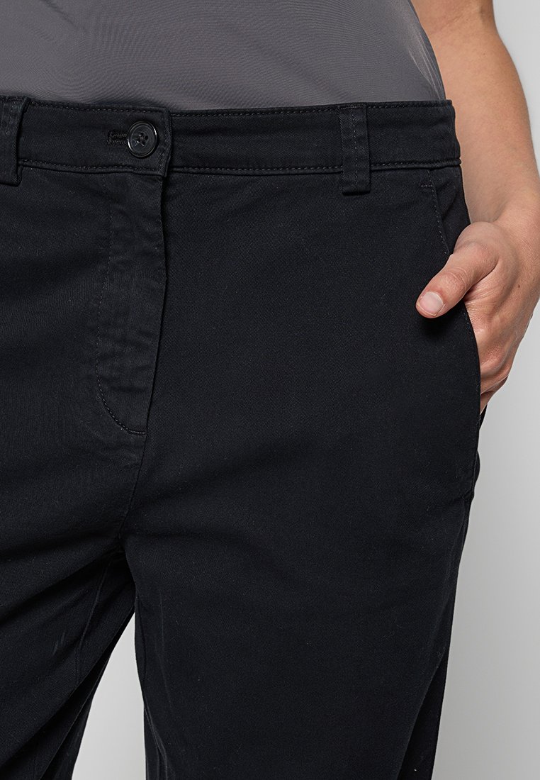 Schwarze Baumwollhose mit geradem Schnitt, ausgestattet mit einem einzelnen Knopfverschluss, Gürtelschlaufen und Seitentaschen. Der Stoff hat eine glatte Textur.