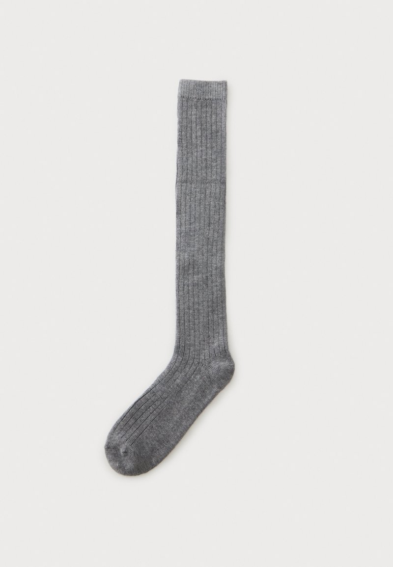 Une seule chaussette longue grise côtelée posée à plat sur un fond blanc, montrant toute la longueur du pied jusqu'à la bordure.