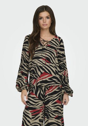 Maglietta a maniche lunghe color beige con strisce zebrate nere e rosse, caratterizzata da una scollatura a V con dettaglio a fiocco e maniche arricciate. Abbinata a pantaloni coordinati.