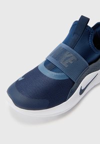 Chaussure de sport bleue avec un dessus en mesh, sangle élastique comportant le logo "NIKE", bout arrondi et semelle rembourrée.