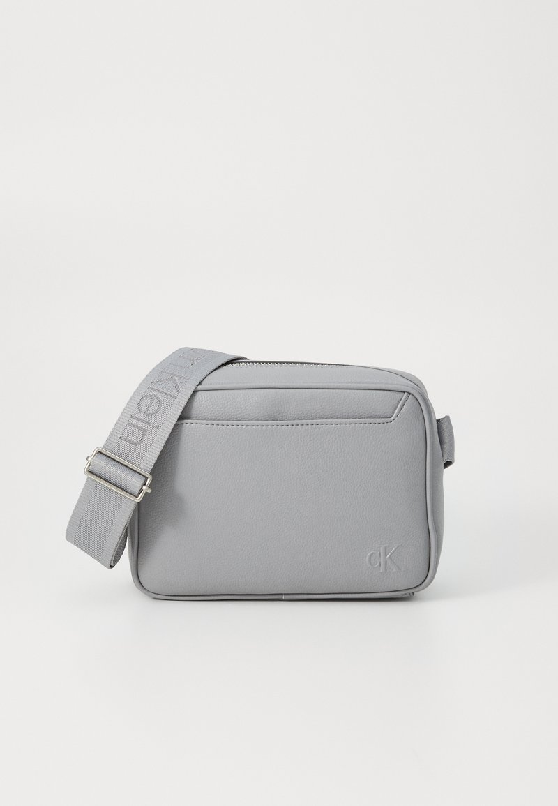 Grijs synthetisch leren crossbody tas met een plat ontwerp, verstelbare stoffen schouderband en geperst logo aan de voorkant. Ritssluiting.