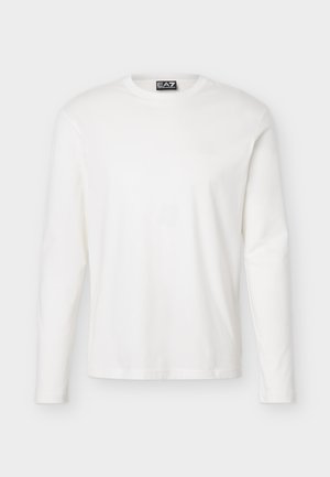 Balta, garām piedurknēm, apaļas kakla izgriezuma krekls ar nelielu melnu EA7 Emporio Armani logotipa etiķeti kakla aizmugurē.